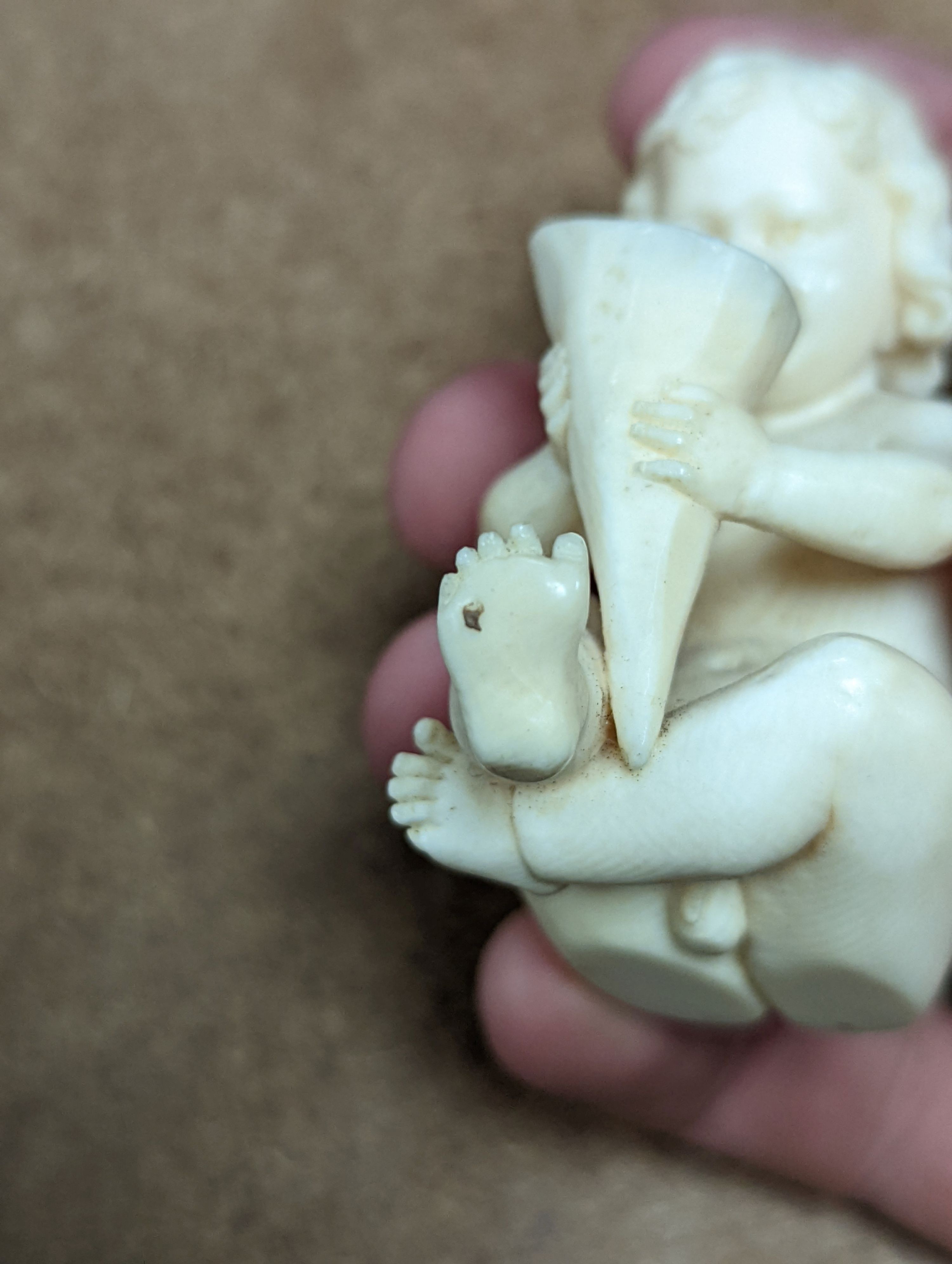 A 19th century Continental carved ivory figure of a child holding a cornucopia - 7cm tall